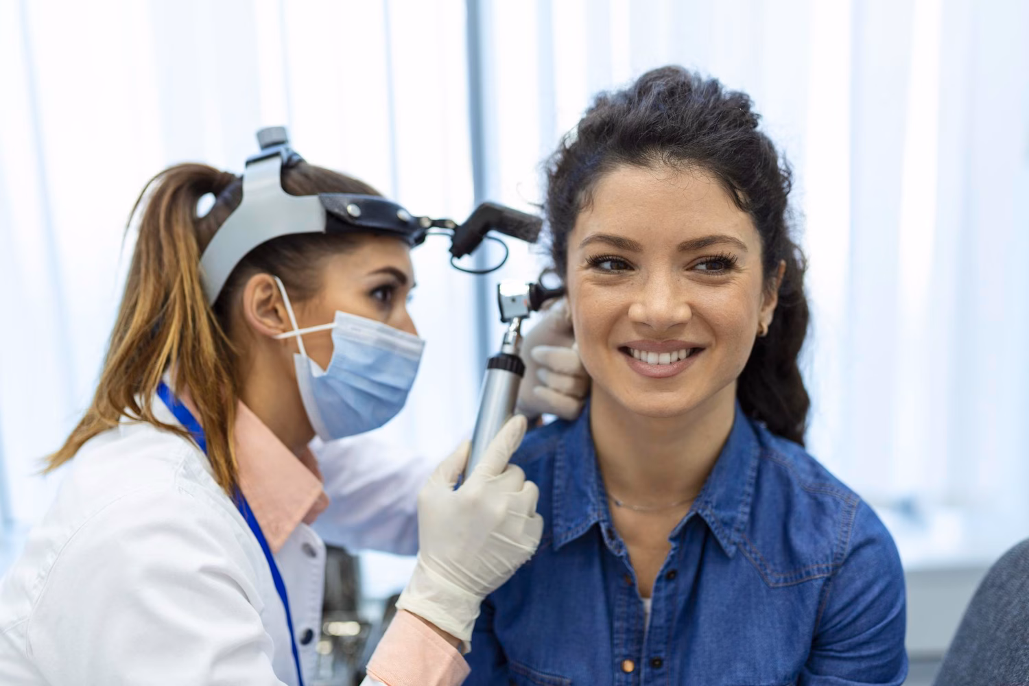 A clinician examining a patient's ear with an otoscope