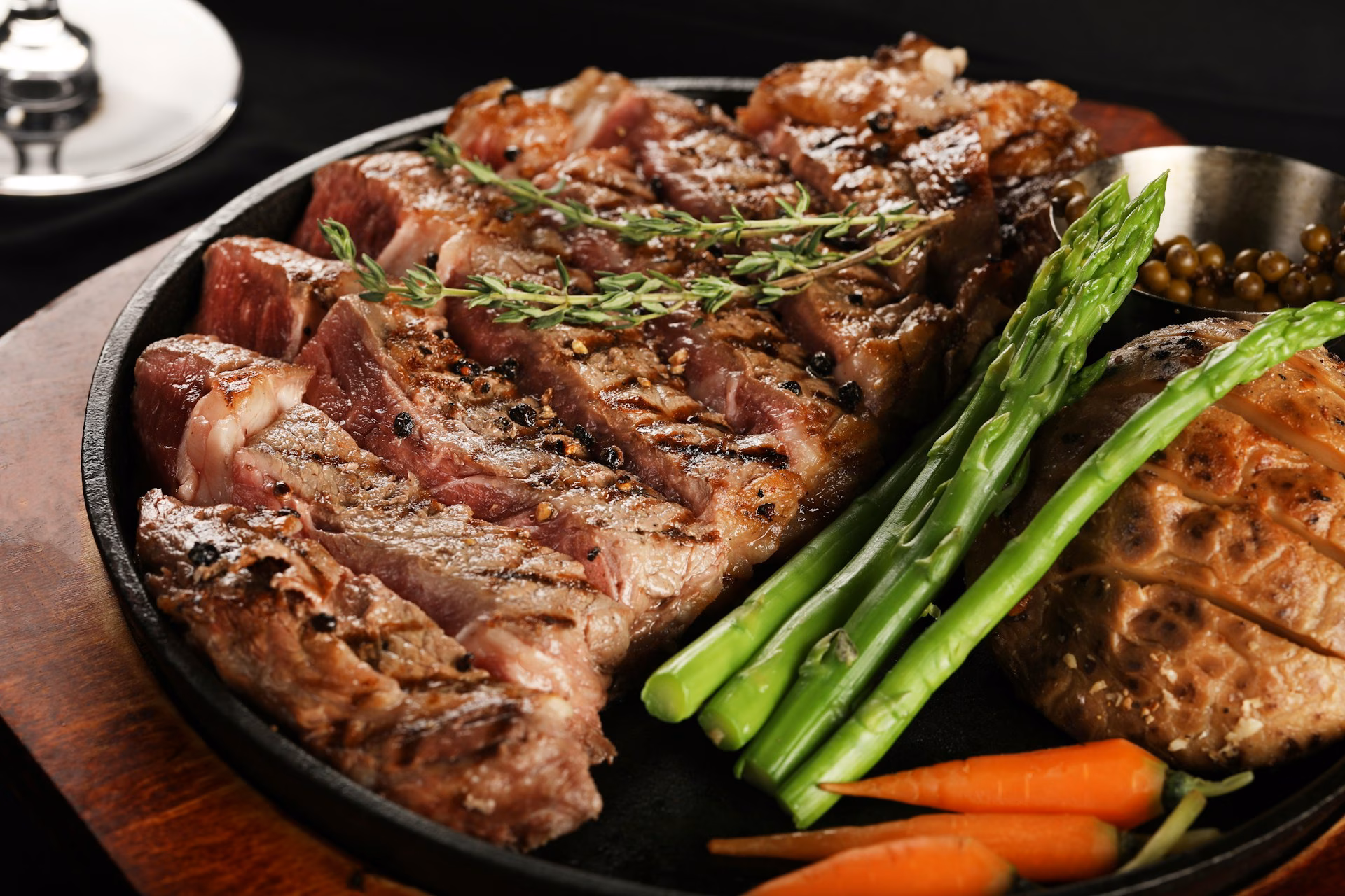 A cooked steak in a pan with asparagus and rosemary